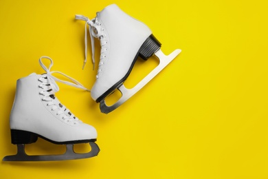Photo of Pair of figure ice skates on yellow background, flat lay. Space for text