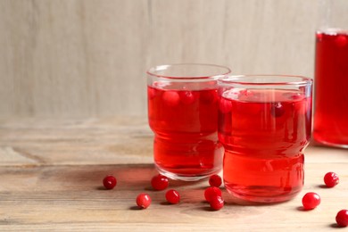 Tasty cranberry juice in glasses and fresh berries on wooden table, closeup. Space for text