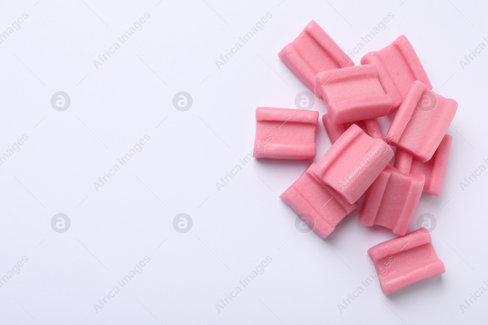 Photo of Tasty pink chewing gums on white background, flat lay. Space for text