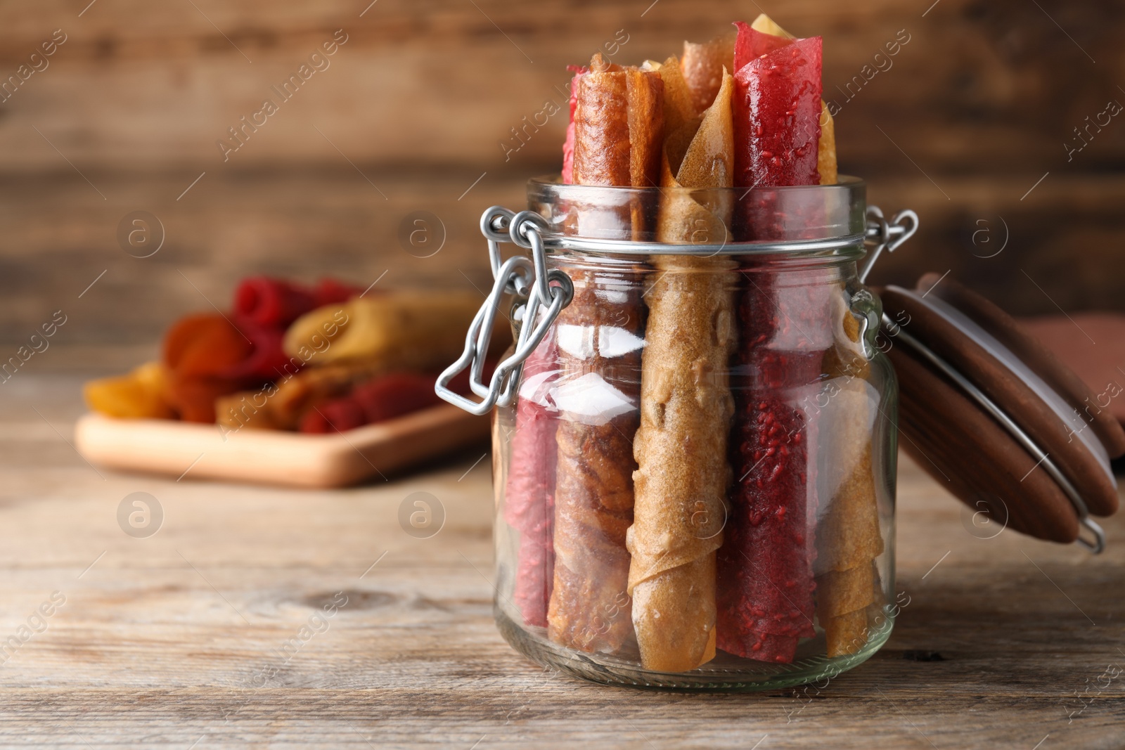 Photo of Delicious fruit leather rolls on wooden table. Space for text