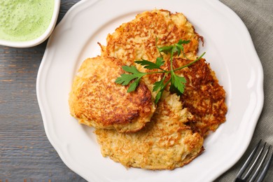 Tasty parsnip cutlets with parsley served on grey wooden table, flat lay