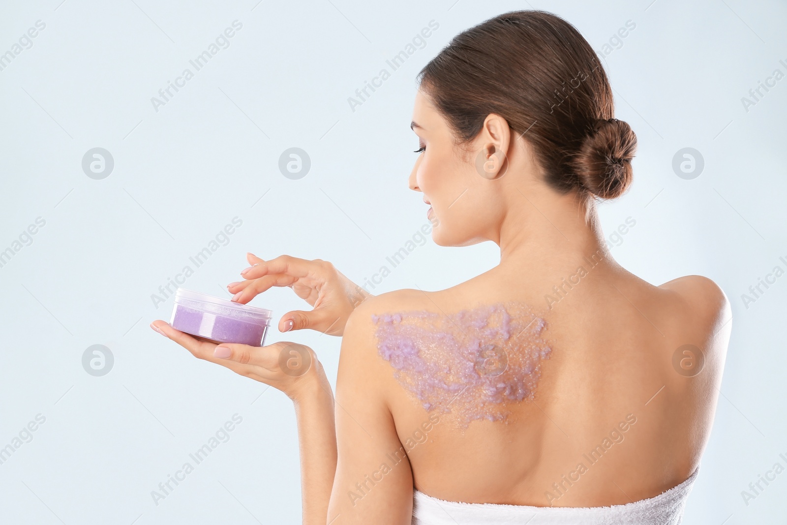 Photo of Young woman applying natural scrub on her body against light background