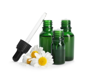 Photo of Chamomile flowers and cosmetic bottles of essential oil on white background