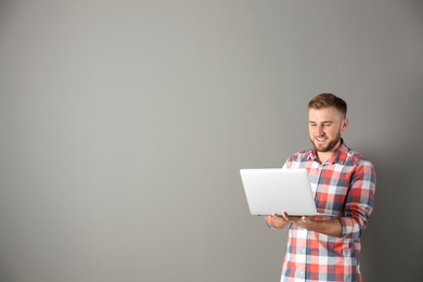 Photo of Young handsome man with laptop on color background