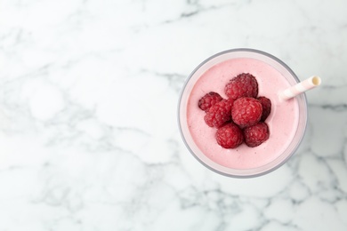 Yummy raspberry smoothie in glass on white marble table, top view. Space for text 
