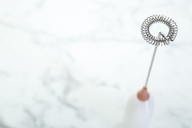 Photo of Milk frother wand on white marble table. Space for text