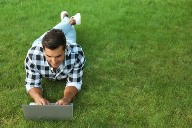 Photo of Portrait of young man with laptop outdoors. Space for text