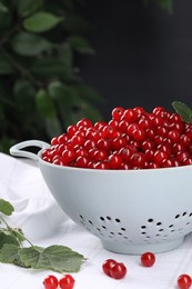 Photo of Ripe red currants in colander on table. Space for text