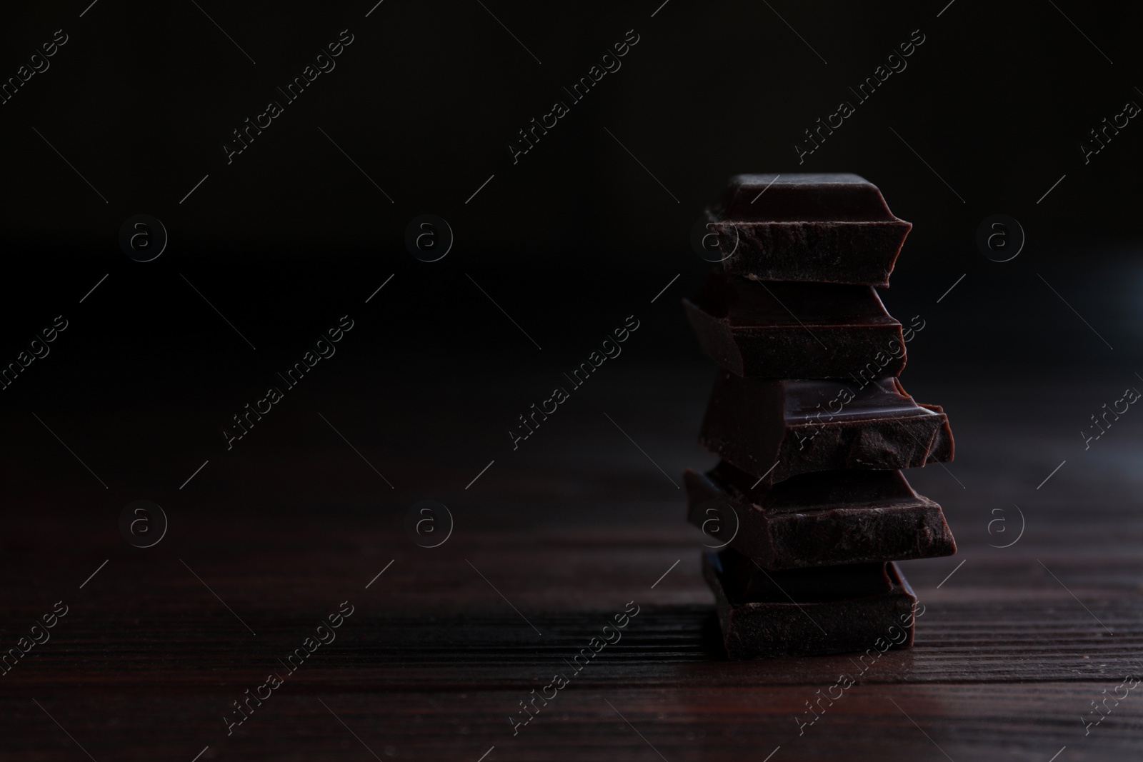 Photo of Delicious dark chocolate on wooden table. Space for text