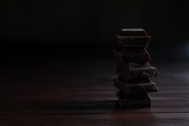 Photo of Delicious dark chocolate on wooden table. Space for text