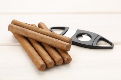 Photo of Cigars and guillotine cutter on white wooden table