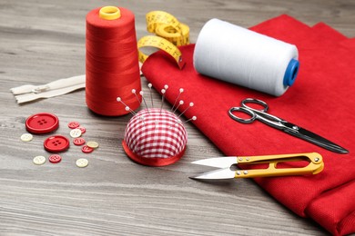 Photo of Different sewing supplies and fabric on wooden table