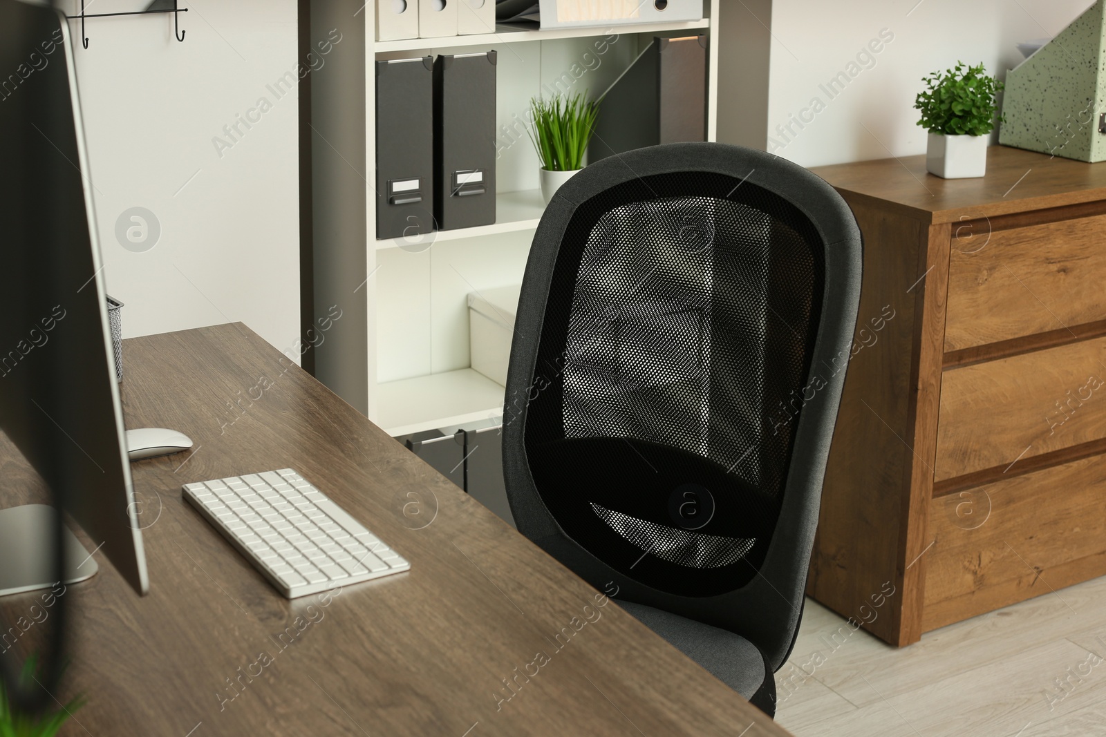 Photo of Stylish office chair near desk with computer in room. Interior design