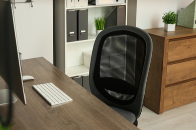 Stylish office chair near desk with computer in room. Interior design