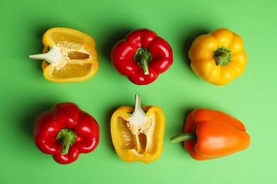 Flat lay composition with ripe bell peppers on green background