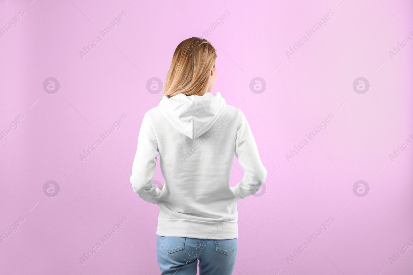 Photo of Woman in hoodie sweater on color background. Space for design