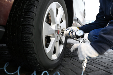 Photo of Mechanic checking tire air pressure at car service, closeup