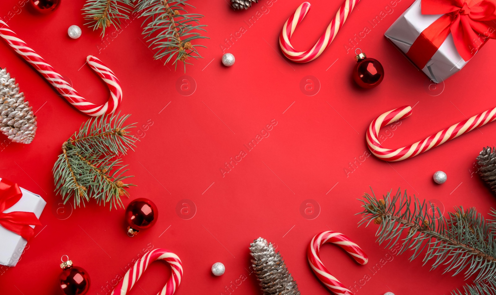 Photo of Frame of candy canes and Christmas decor on red background, flat lay. Space for text