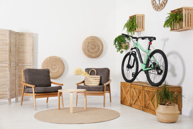 Photo of Modern bicycle and comfortable armchairs in stylish living room interior