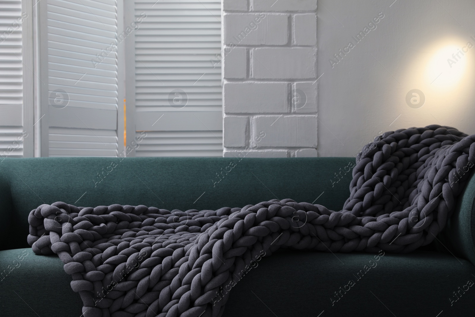 Photo of Soft chunky knit blanket on sofa in room