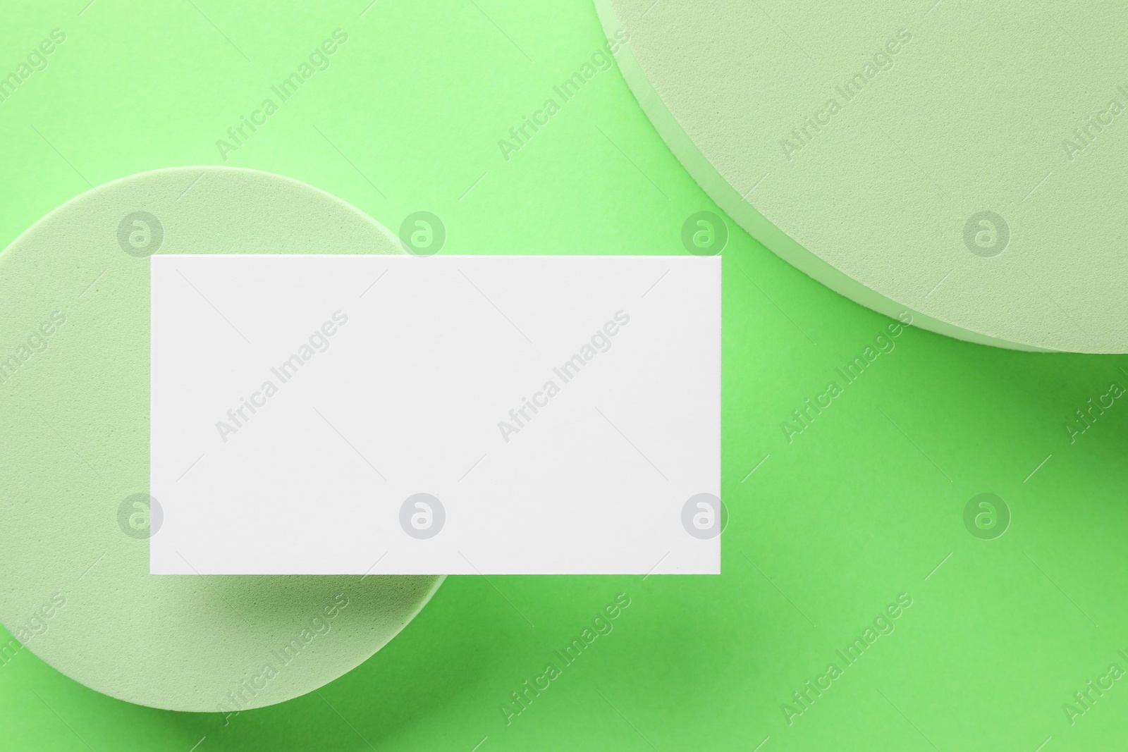 Photo of Empty business card and decorative elements on light green background, top view. Mockup for design