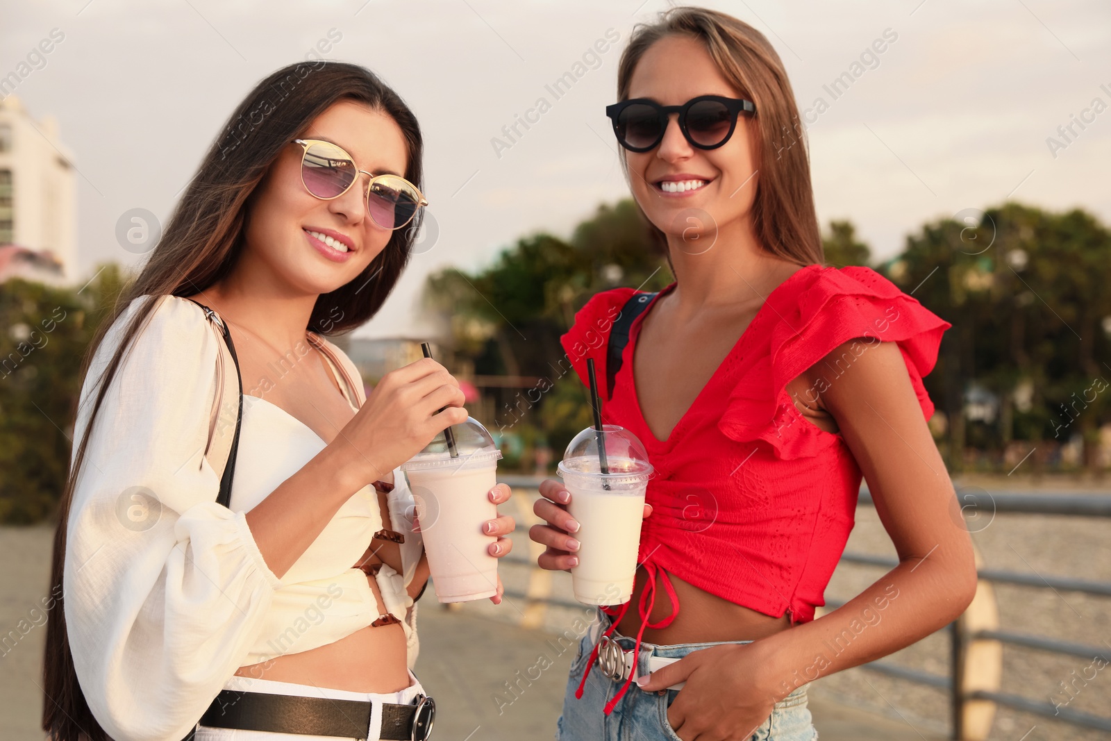 Photo of Beautiful young women with tasty milk shakes outdoors