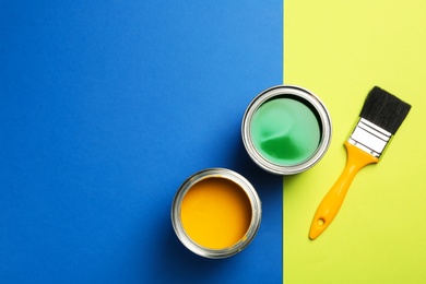Photo of Open paint cans, brush and space for text on color background, top view