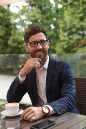 Photo of Smiling handsome bearded man with coffee in outdoor cafe