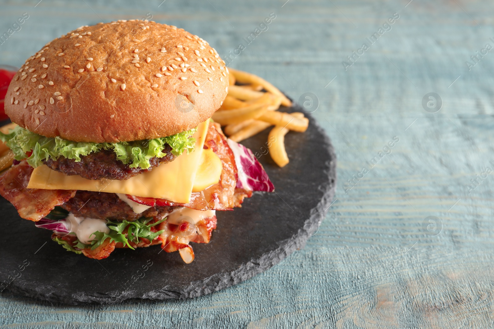 Photo of Tasty double burger with bacon on slate plate