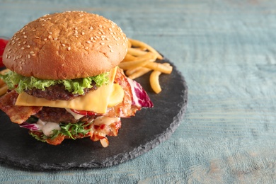 Photo of Tasty double burger with bacon on slate plate