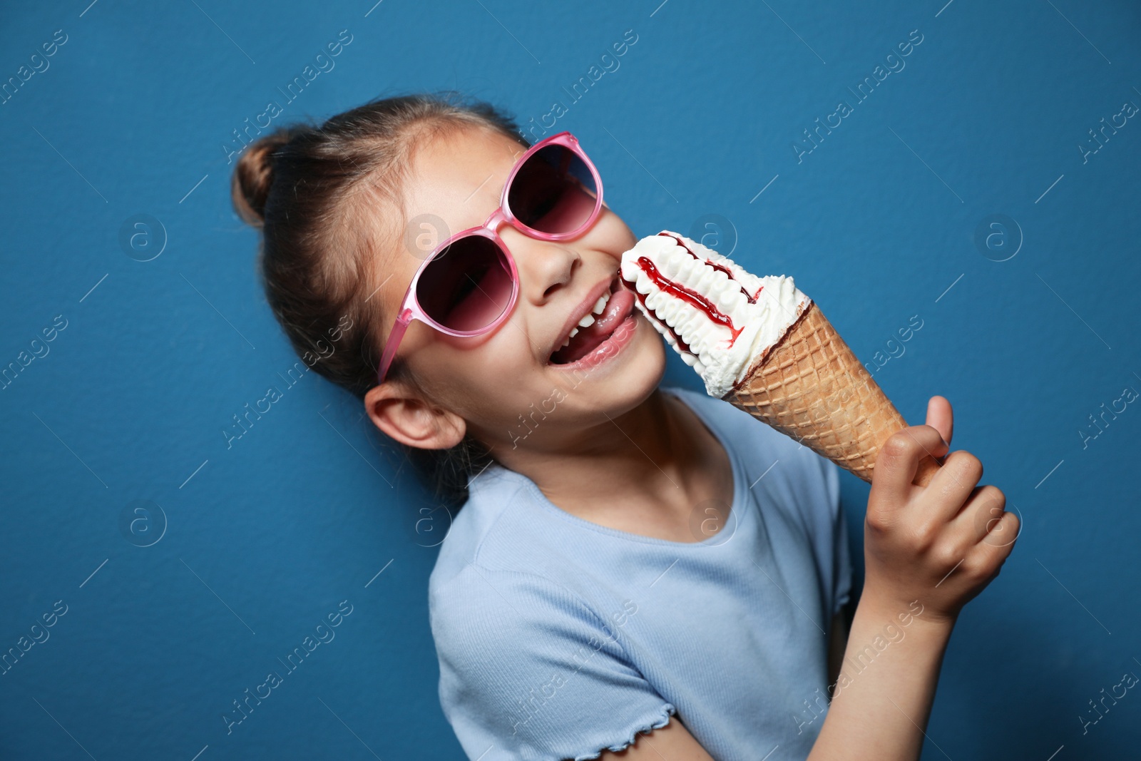 Photo of Adorable little girl with delicious ice cream against color background