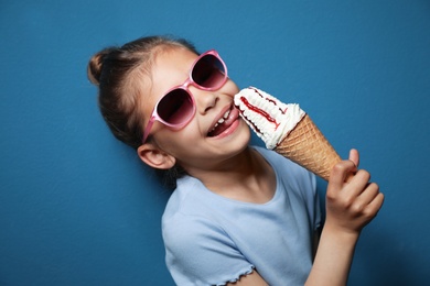 Photo of Adorable little girl with delicious ice cream against color background