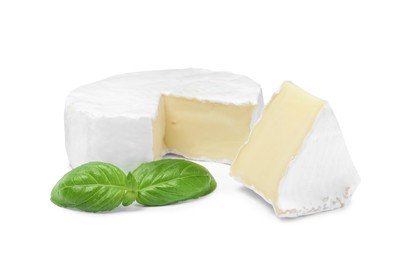 Photo of Tasty cut brie cheese with basil on white background