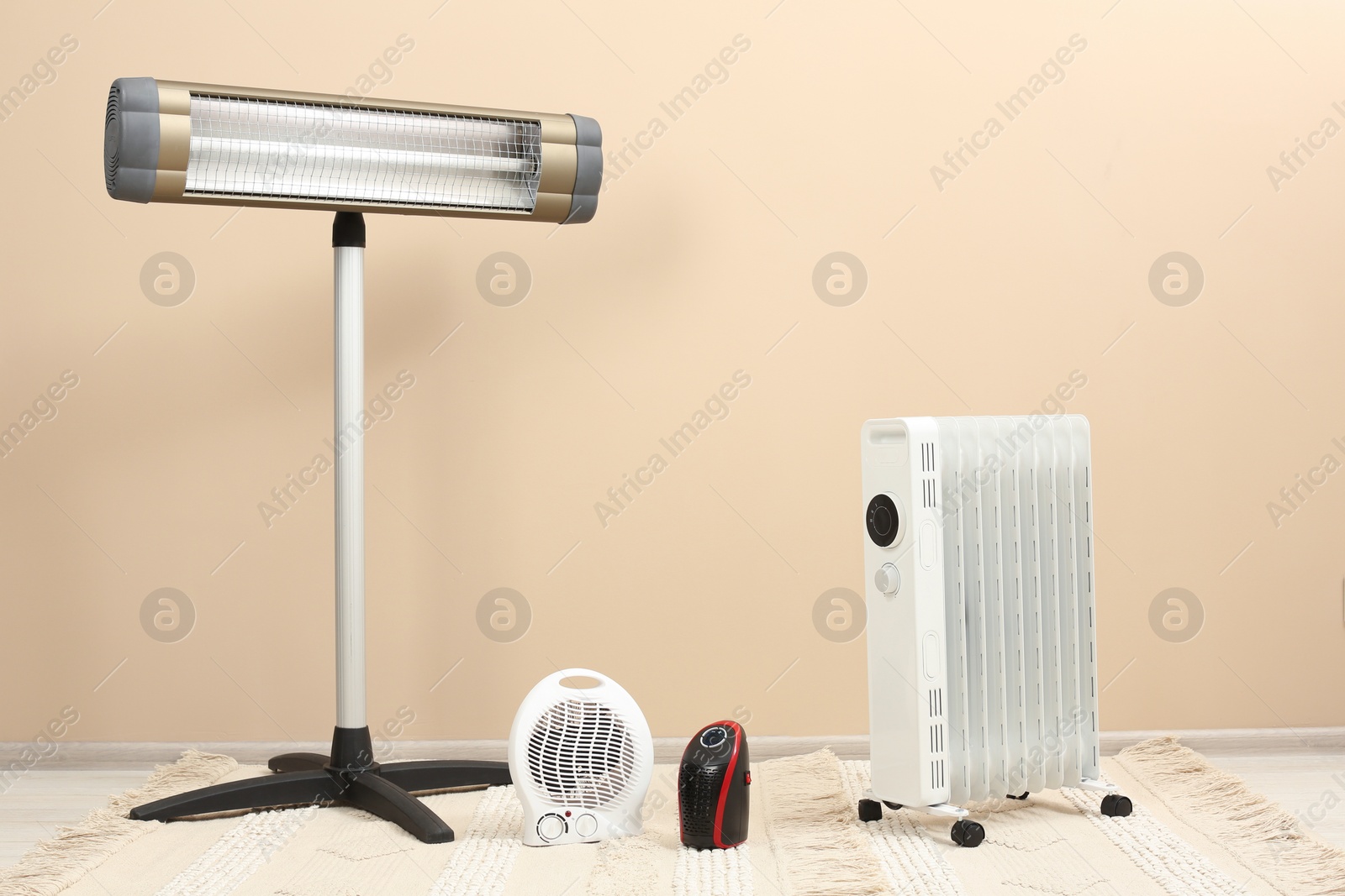 Photo of Different modern electric heaters on floor near beige wall indoors