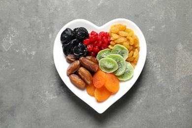 Plate with different dried fruits on grey background, top view. Healthy lifestyle