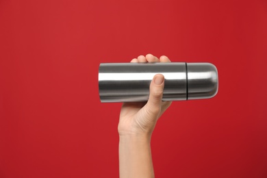 Photo of Woman holding modern thermos on red background, closeup