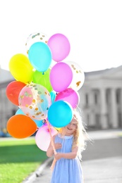 Photo of Cute girl with colorful balloons outdoors on sunny day