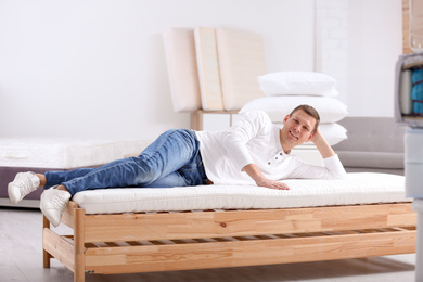 Photo of Man testing soft mattress in furniture store