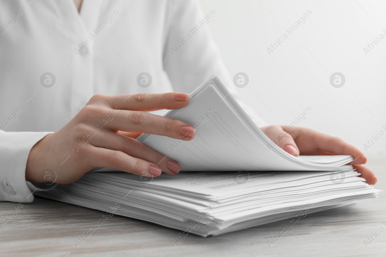 Photo of Woman reading documents at wooden table in office, closeup