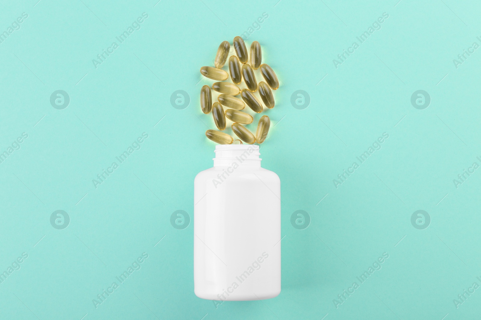 Photo of Bottle and vitamin capsules on turquoise background, top view