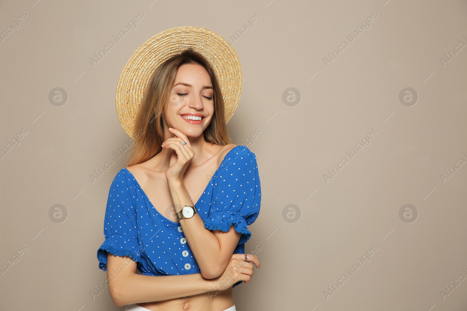 Photo of Beautiful young woman wearing straw hat on beige background, space for text. Stylish headdress