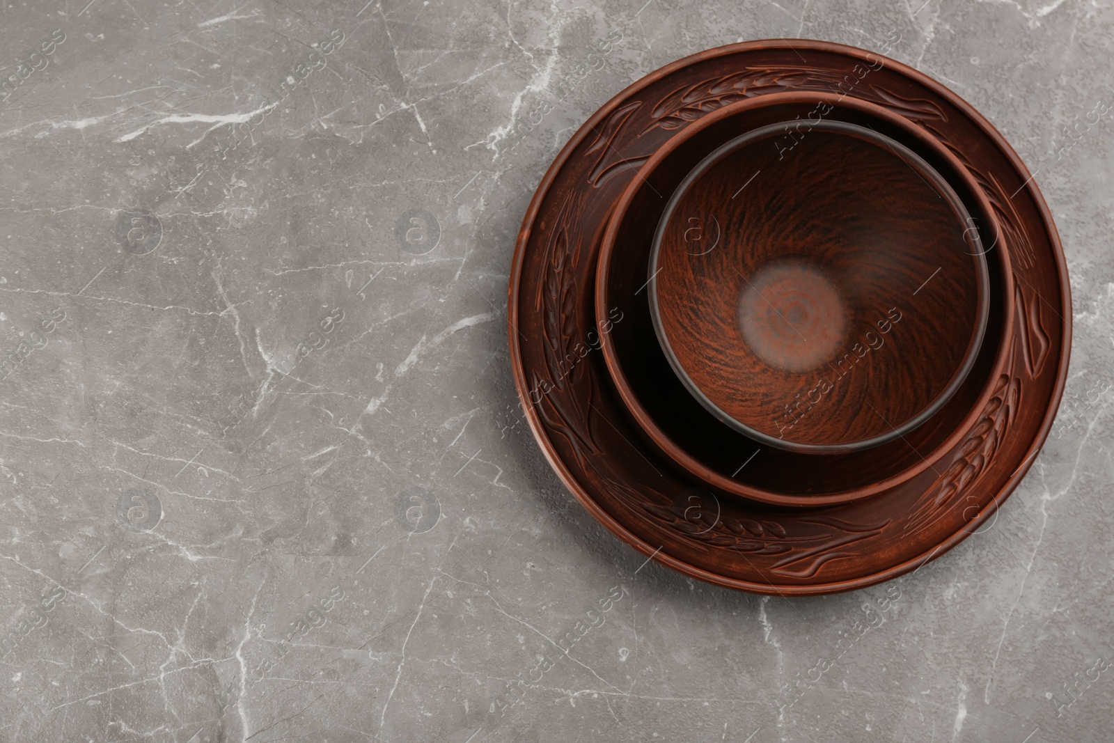 Photo of Set of clay utensils on grey marble table, top view. Space for text