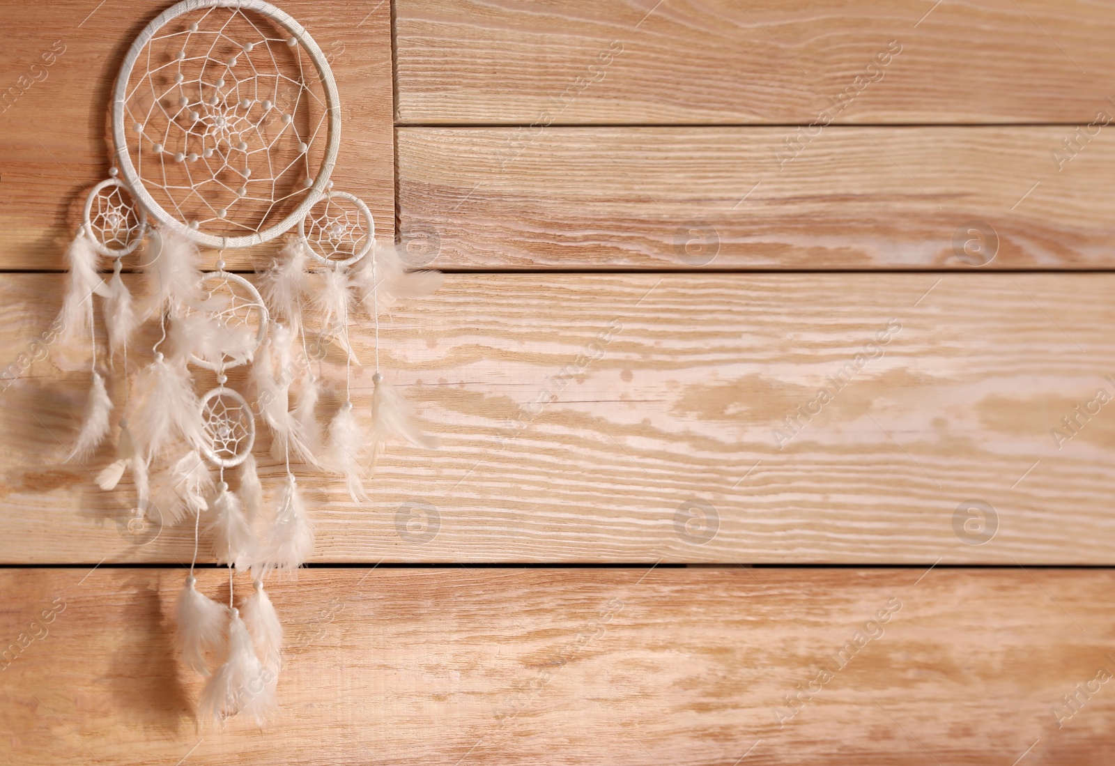 Photo of Beautiful dream catcher hanging on wooden wall, space for text