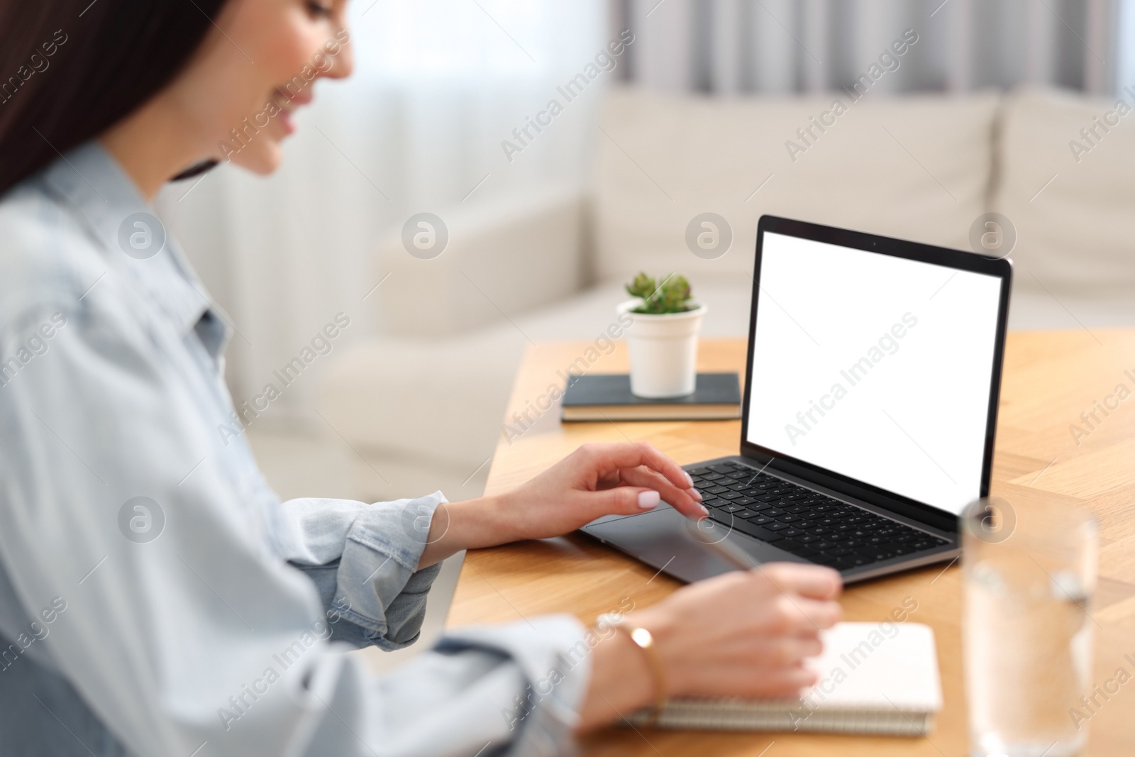 Photo of Young woman watching webinar at table in room, closeup