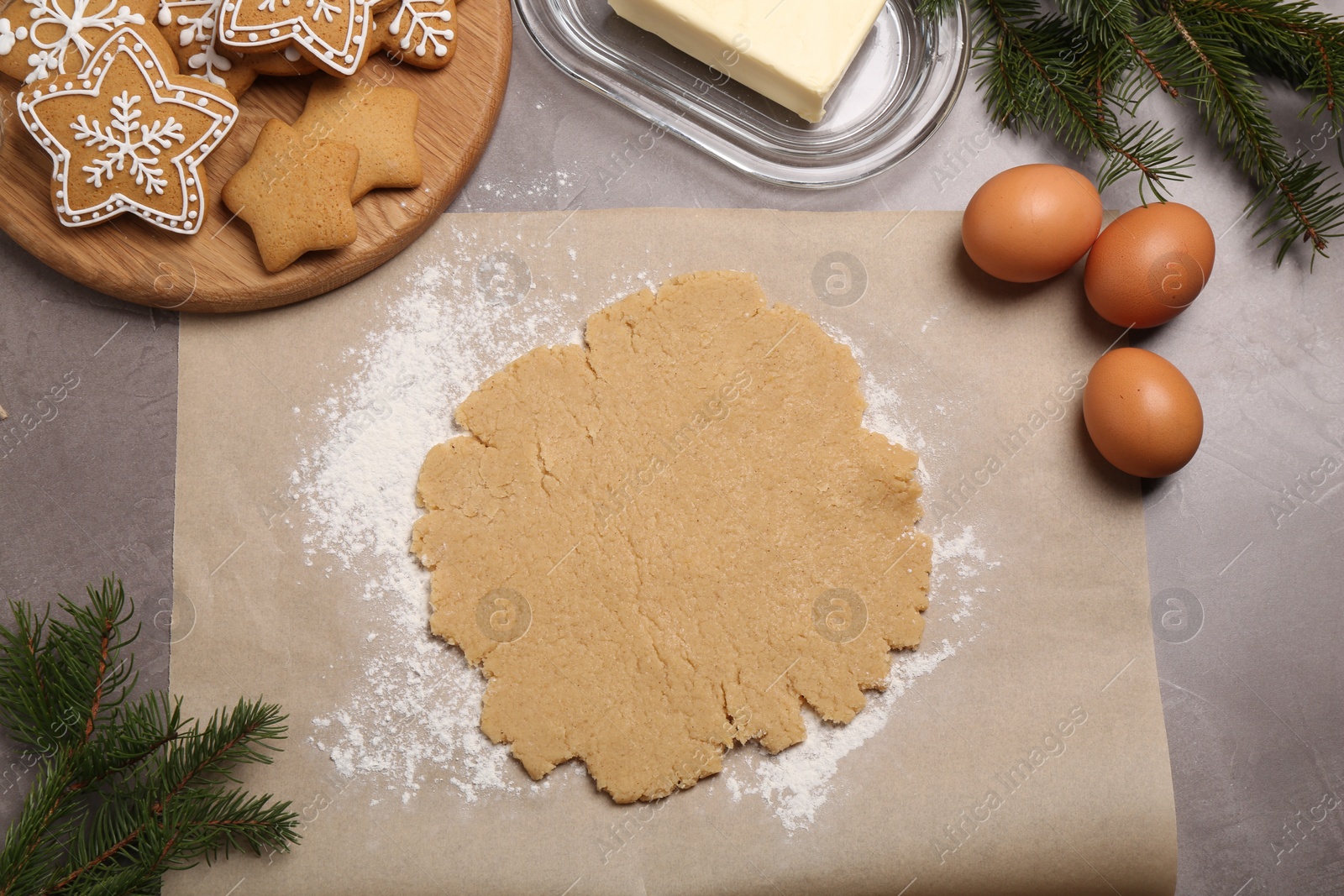 Photo of Making Christmas cookies. Flat lay composition with ingredients and raw dough on grey table