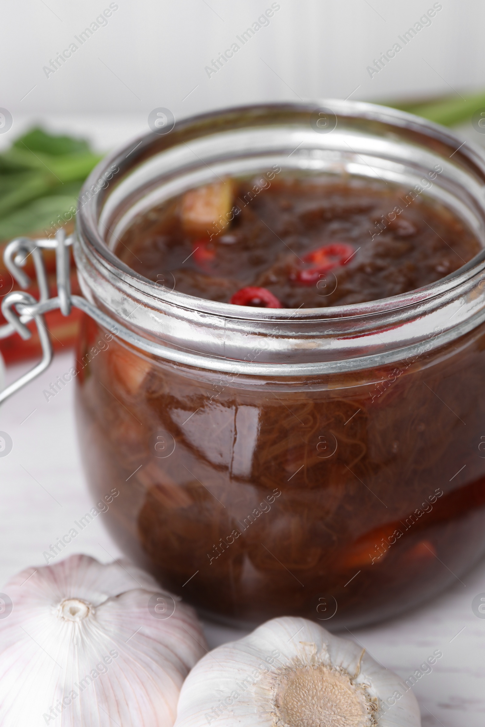 Photo of Tasty rhubarb sauce and garlic on white table, closeup