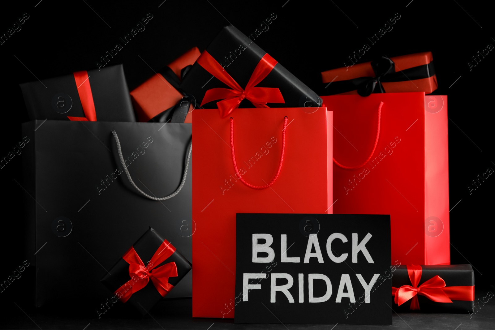 Photo of Paper shopping bags and gift boxes on dark background. Black Friday sale