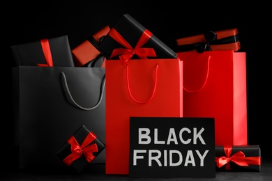 Paper shopping bags and gift boxes on dark background. Black Friday sale