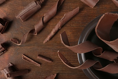 Photo of Flat lay composition with chocolate curls on wooden background