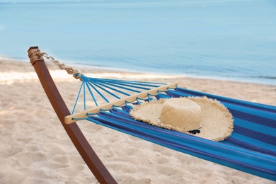 Photo of Comfortable hammock with straw hat at seaside. Summer vacation